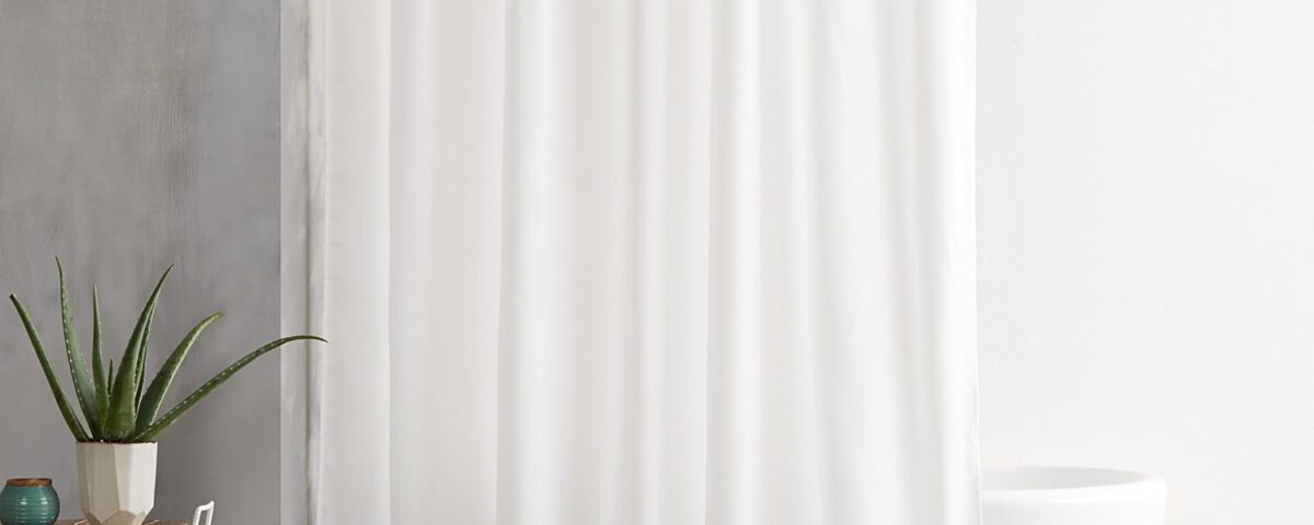 Cortina de ducha de tela Amazon Basics blanca de 180x180 cm colgada en un baño moderno