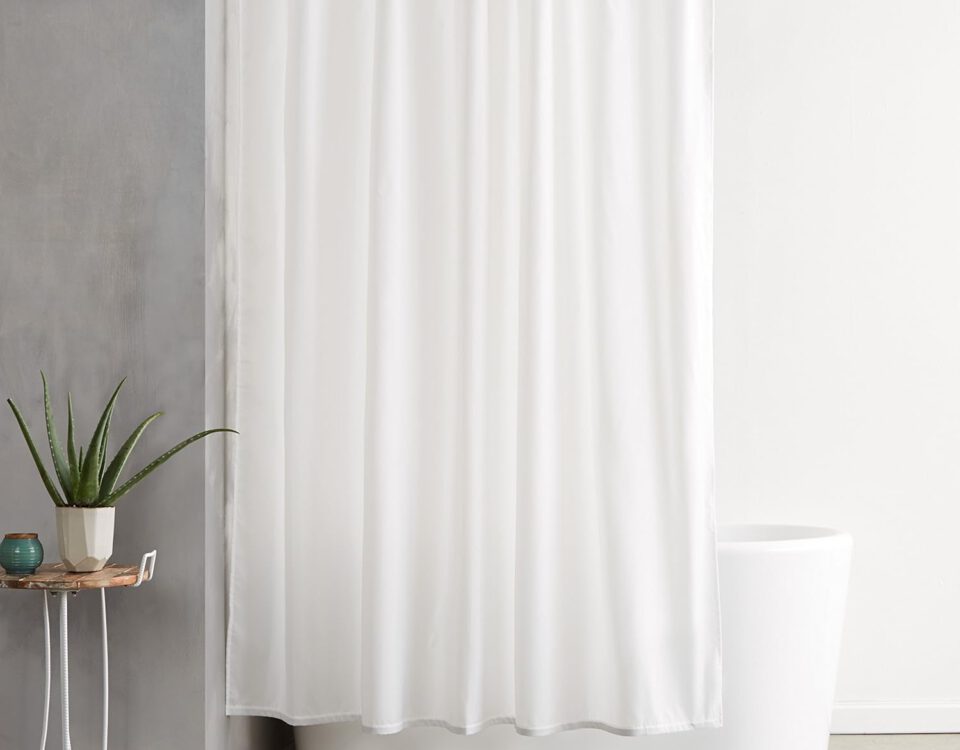 Cortina de ducha de tela Amazon Basics blanca de 180x180 cm colgada en un baño moderno