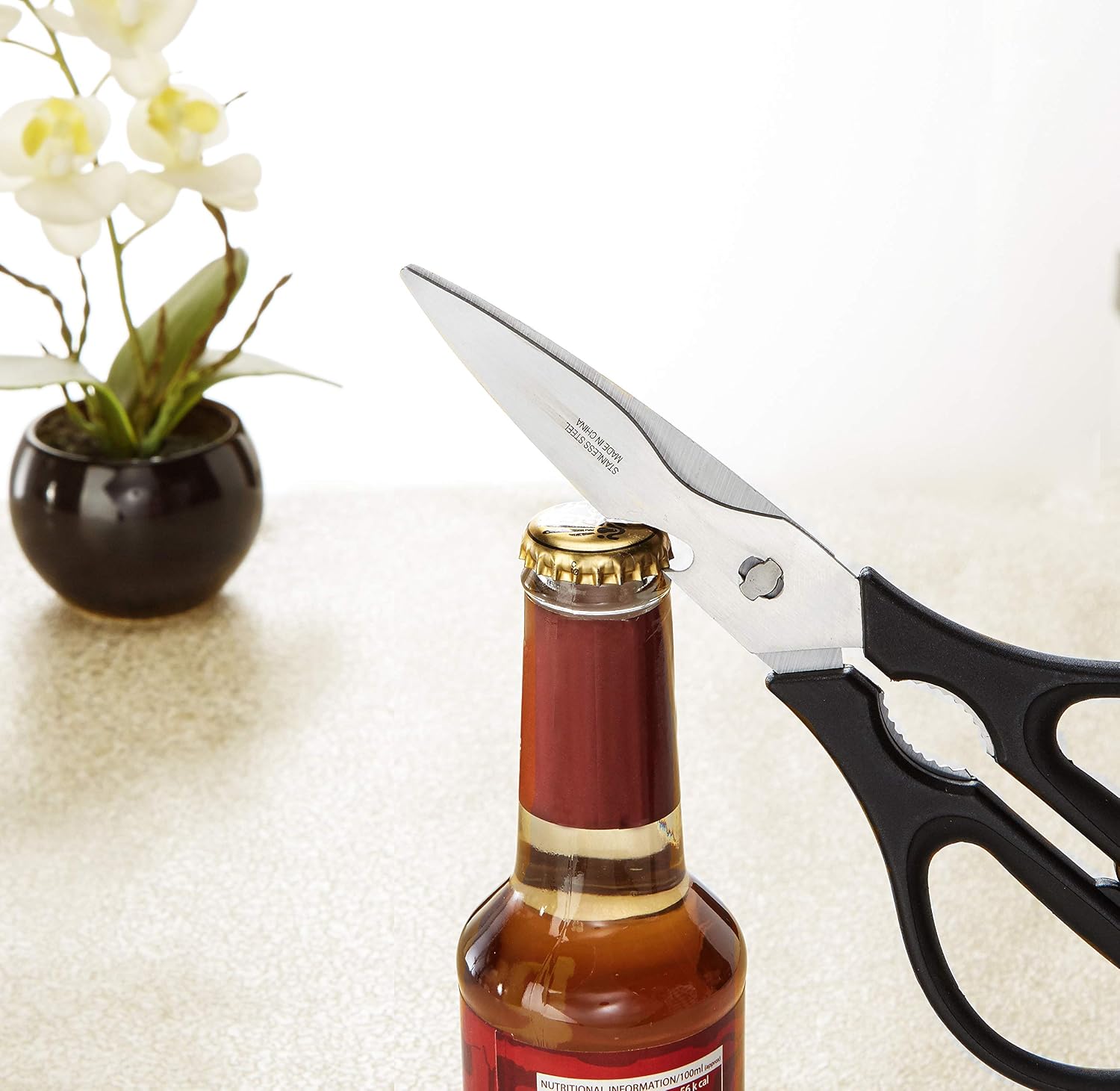Tijeras de cocina Amazon Basics usadas como abrebotellas para abrir una botella de cerveza